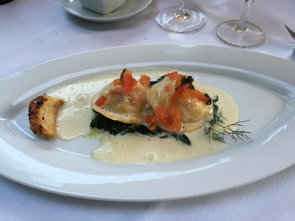 Freshmade ravioli with Atlantic lobster and scallops filling on a bed of spinach with tomatoes and basil.